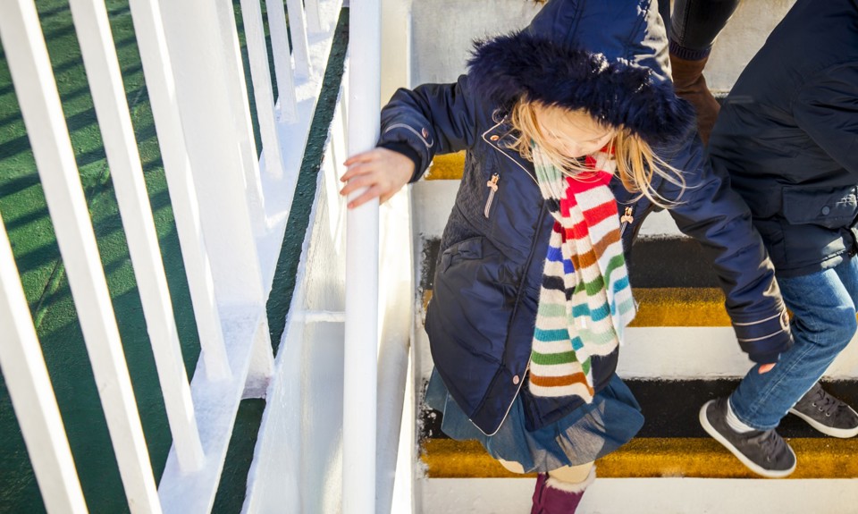 little girl walking down the stairs of the boat outside holding onto the handrail