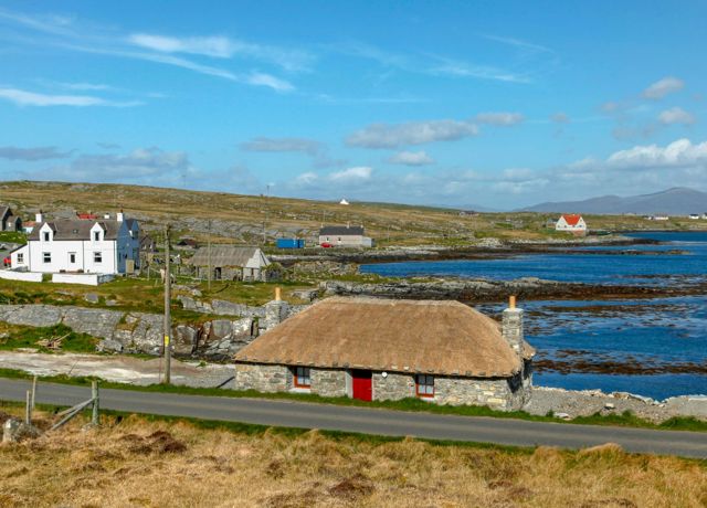  Isle of Berneray - Thatched cottage and a village in the background