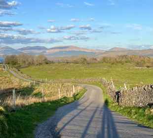 A winding single track road, with hills in the background, Lismore.